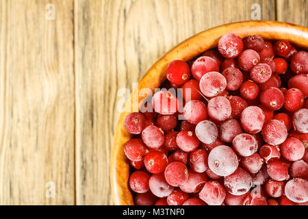 Das gefrorene Preiselbeeren in eine hölzerne Schüssel. Im rustikalen Stil. Der Frost auf der Beeren. Stockfoto