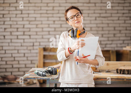 Fleißige professionelle Arbeiterin mit Stift und Tablett in Werkstatt Stockfoto