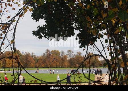 Ein Blick durch die aus der versunkenen Garten im Kensington Palace zu den runden Teich im Park Kensington Gardens mit um Touristen zu Fuß Stockfoto