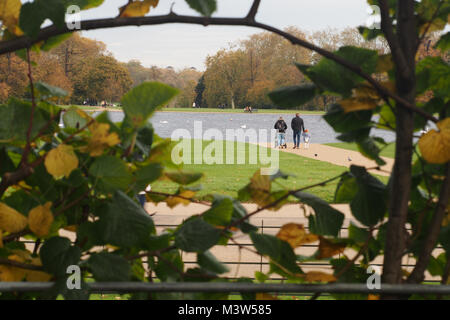 Ein Blick durch die aus der versunkenen Garten im Kensington Palace zu den runden Teich im Park Kensington Gardens mit um Touristen zu Fuß Stockfoto