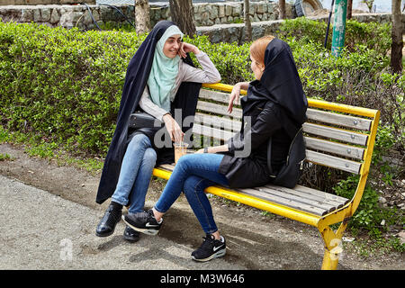 Teheran, Iran - 28. April 2017: zwei iranische Frauen in hijabs sitzen auf einer Bank im Park und zu sprechen. Stockfoto