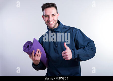 Junge Athlet Mann hält eine Yogamatte Stockfoto