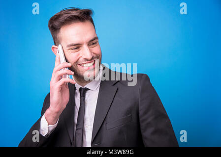Junge Unternehmer in einem freundlichen Gespräch an seinem Telefon Stockfoto