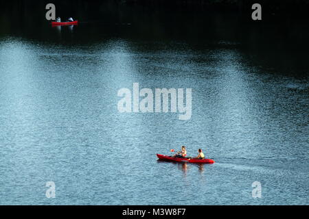 AUSTIN, Texas - 30. SEPTEMBER 2017: Zwei rote Kajaks navigieren Licht und die dunklen Wasser des Colorado River ab Congress Bridge in Austin, Texas. Stockfoto