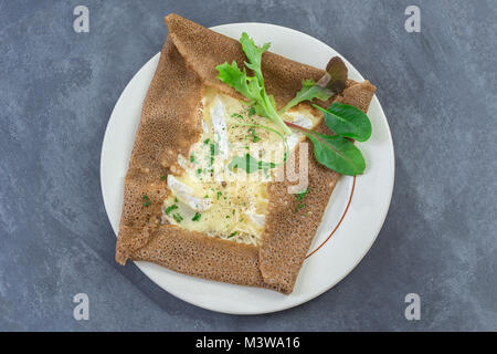 Galette de Sarasin - Französisch Buchweizen Crepe mit Camembert und Salat auf einem grauen Schiefer Hintergrund Stockfoto