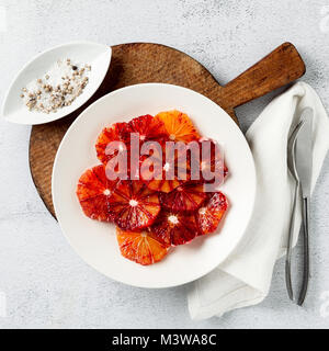 In Scheiben geschnitten rot orange Slices auf einer Platte. Grundlage für das Dessert oder Salat. Sommer Stil auf einem Stein weiß Tisch Stockfoto