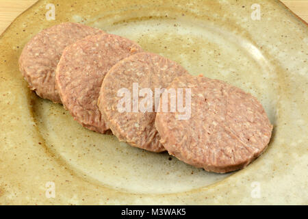 Frozen raw Hamburger Pastetchen Auftauen auf Keramik Platte wie Grillen Vorbereitung Stockfoto
