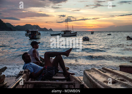 Zwei Fischer in einem hölzernen Boot am Strand in Taganga, Kolumbien Stockfoto