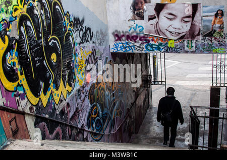 Ein Mann hinunter Treppe durch eine Gasse in Graffiti und Street Art in Valparaiso, Chile abgedeckt Stockfoto