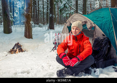 Nachdenklich touristische Frau sitzt in der Nähe von einem Zelt in einem Winter Forest Stockfoto