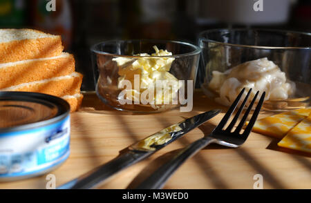 Weißes Brot, Butter in Glasschale, Mayo in Glas Teller, Messer und Gabel, un geöffnet von Thunfisch. Licht Holz Hintergrund. Das spiegeln. Stockfoto