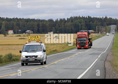 KOSKI TL, Finnland - 15. SEPTEMBER 2017: Pilot Fahrzeug warnt Verkehr der Überbreite Maschinen Transport durch eine rote Scania R580 semi Trailer von Kosken Autok Stockfoto