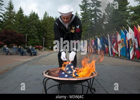 BANGOR, Washington (14. Juni 2017) Elektroniker (Kommunikation) 1. Klasse Jonathan Diquattro, von Columbus, Georgia, Trident Training Service Bangor zugeordnet, Orte die Überreste eines US-Flagge zu einem Brand während einer Flagge in den Ruhestand Zeremonie am Marinestützpunkt Kitsap - Bangor. Wenn eine US-Flagge abgenutzt, zerrissen, blasse oder stark verschmutzt, die Flagge mit der Würde und Achtung, die es in den Ruhestand versetzt. Die traditionelle Methode ist die Fahne in Stücke zu schneiden, trennen die 13 Streifen von Kanton und verbrennen Sie separat in einer respektvollen Weise. (U.S. Marine Foto von Massenkommunikation S Stockfoto