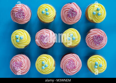 Farbenfrohe gelbe Zitrone und rosa Herzen Cupcakes auf blauem Hintergrund. Muster Stockfoto