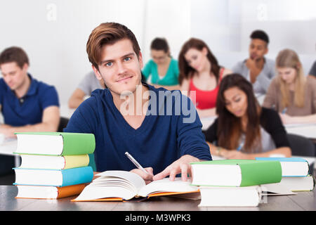 Portrait eines glücklichen männlichen Schüler im Klassenzimmer sitzen Stockfoto