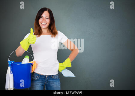 Portrait einer weiblichen Hausmeister mit der Reinigung der Geräte Gestik Daumen hoch Stockfoto