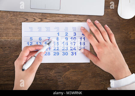 Nahaufnahme der Kaufmann Hand Zeichnung Roter Kreis auf dem Kalender Datum mit Stift Stockfoto