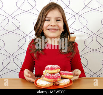 Glückliche kleine Mädchen mit süßen Krapfen Stockfoto