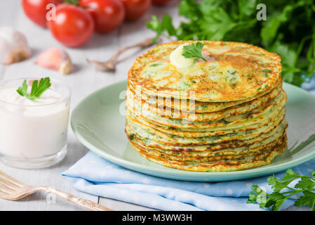 Viele Pfannkuchen mit frischen Kräutern und saure Sahne Soße auf einer hölzernen Tisch. Traditionelle ukrainische oder russische Pfannkuchen. Maslenitsa. Traditionelle Gerichte auf Th Stockfoto