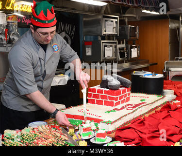 NAVAL BASE KITSAP Bremerton, Washington (31. 25, 2017) U.S. Navy kulinarische Specialist 2. Klasse Anthony Taylor, von Richmondville, Ga, serviert Kuchen während ein Weihnachtsessen an Bord Nimitz (CVN 68), Dez. 25, 2017, im Marinestützpunkt Kitsap Bremerton. Der Nimitz befindet sich derzeit in der Vorbereitung für eine geplante schrittweise Verfügbarkeit Puget Sound Naval Shipyard und Intermediate Maintenance Facility, wo das Schiff geplant sind, Wartung und Upgrades. (U.S. Marine Foto von Mass Communication Specialist 3. Klasse Kennishah J. Maddux) 171225-N-UD 618-087 von Naval Base Kitsap (NBK) Stockfoto