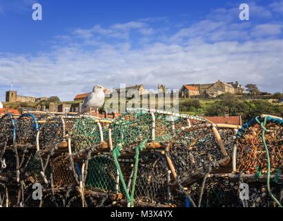 Whitby: eine Möwe sitzt auf einem Lobster Pot mit einem Hügel Kirche im Hintergrund. Stockfoto