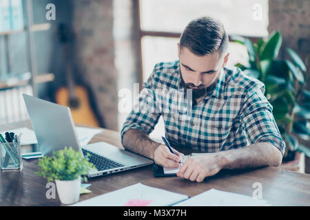 Aufmerksame smart clever intelligente männliche Student trägt kariertem Hemd ist Hausaufgaben zu Hause vor der modernen Computer Stockfoto
