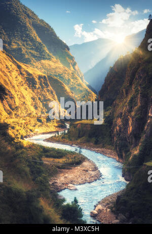 Bunte Landschaft mit hohen Berge des Himalaja, schön geschwungene Fluss, grünen Wald, blauer Himmel mit Wolken und gelbe Sonnenlicht bei Sonnenuntergang im Herbst Stockfoto