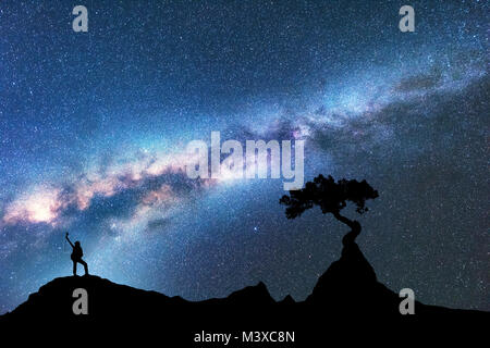 Milchstraße, die Silhouette der Frau und Baum aus dem Felsen auf dem Berg in der Nacht. Raum Hintergrund mit Sternenhimmel, schöne Galaxie und Mädchen. B Stockfoto