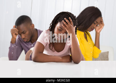 Eltern sitzen auf dem Sofa streiten Lautstark hinter Mädchen für Ihre Ohren Stockfoto