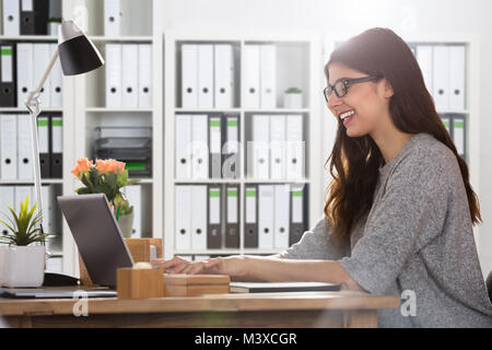 Porträt eines lächelnden Jungen Geschäftsfrau mit Laptop Stockfoto