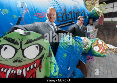 Ein Mann in einem chub Anzug und Anil Agarwal Maske holdstwo der vielen Köpfen der riesigen Vedanta Monster, die das Unternehmen in die Gruppe für die envrionmental und Menschenrechtsverletzungen in der Welt. Stockfoto