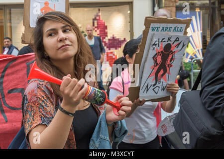 Eine Frau Pumpen ein Horn in den Vereinigten Stimmen der Welt Protest in der Straße draußen Sotheby's für die wiedereinsetzung von 2 Arbeiter entlassen, weil sie für die Lohnfortzahlung im Krankheitsfall, Urlaubsgeld und Renten. Stockfoto