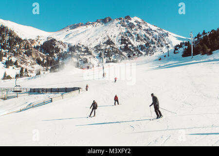 Skifahrer und Snowboarder reiten auf einer Skipiste Mountain Resort auf verschneiten Winter Hintergrund. Getönte retro Foto. ski resort Shymbulak Stockfoto