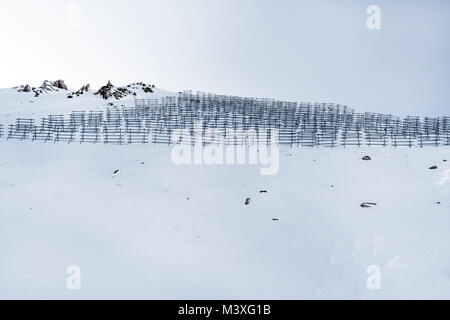 Lawinenschutz Bau auf einem Berg im Winter. Snowy Mountains mit Barrieren in Form von Zäunen. Barrieren aus Schnee Verstopfung ich Stockfoto