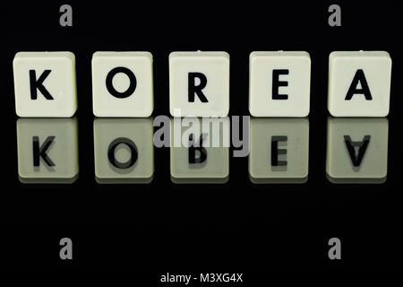 Scrabble auf einem Glastisch. Worte von Buchstaben auf einem Glassubstrat. Die Worte, die Korea. Schwarzer Hintergrund Stockfoto