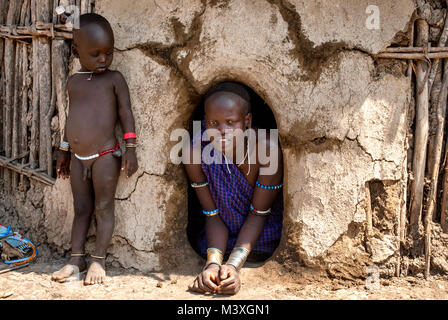 Portrait von Mursi Mutter mit Sohn in der Nähe ihrer Hütte mit einem kleinen Eingang - Äthiopien. © Antonio Ciufo Stockfoto