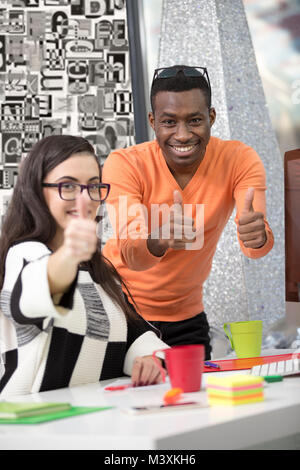 Business, Startup- und Bürokonzept - Frohes kreatives Team mit Daumen nach oben im Büro. Stockfoto