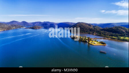 Mächtige breite Hawkesbury River in der Nähe von Mooney Mooney Fischerort an der Autobahn 1 M 1 der Großraum Sydney durch Forstwirtschaft Hügel unter blauem Himmel umgeben. Stockfoto