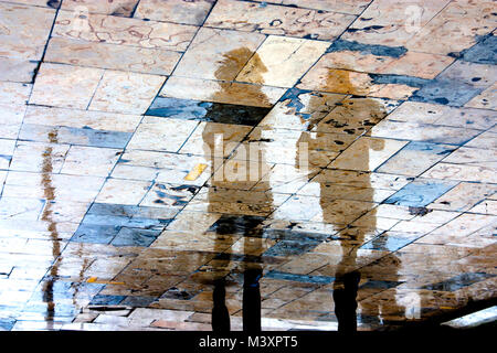 Blurry regnerischen Tag, eine Person, die unter dem Dach der Reflexion Silhouetten auf Nasser City Square in hoher Kontrast Stockfoto