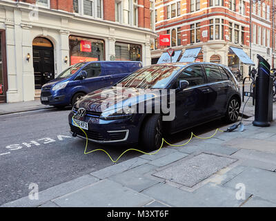 Elektrische Volkswagen Auto an der Straße Aufladepunkt in Westminster, London, UK mit gelben Kabel nach unten Hinterkante Straße an der Vorderseite des Fahrzeugs Stockfoto