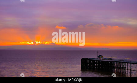 Bunte sunrise mit Meer, Penarth Pier und Himmel Hintergrund in goldenen und magenta Farben. Stockfoto