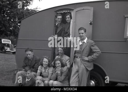 1950er Jahre, historische Bild zeigt einen großen britischen Familie, Gruppe, Männer, Frauen und Kinder und Hund, außerhalb und am Eingang ihre Wohnwagen in einem Feld geparkt, England, Großbritannien sitzen. Stockfoto