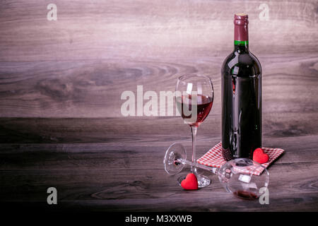 Rotwein Flasche und zwei Gläser Wein mit Deko von roten Herzen auf hölzernen Tisch. Valentines Tag feier Konzept. Kopieren Sie Platz. Stockfoto