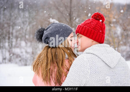 Blick auf Winter Forest mit dem küssen paar in Pullover und Strick Hüte Stockfoto