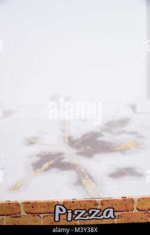 Verwendete Pappe pizza box mit Fettflecken lesft auf dem Boden Stockfoto