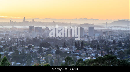 Sonnenuntergang über Oakland und San Francisco dunstig Skylines. Stockfoto