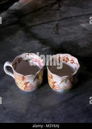Blick nach unten in zwei antiken französischen Teetassen, eine fehlende Griff, auf einem Marmor Oberfläche Stockfoto