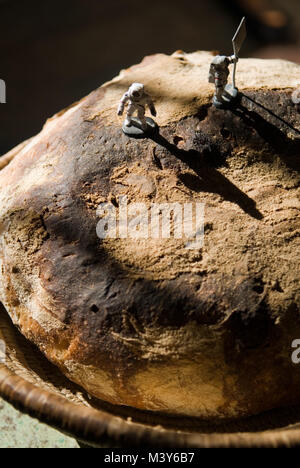 Zwei toy Astronaut zahlen, eine mit einer Fahne, auf den Gipfel eines frisch gebackenen Sauerteig Brot, ähnlich einer Mondlandung, in einer französischen Küche Stockfoto