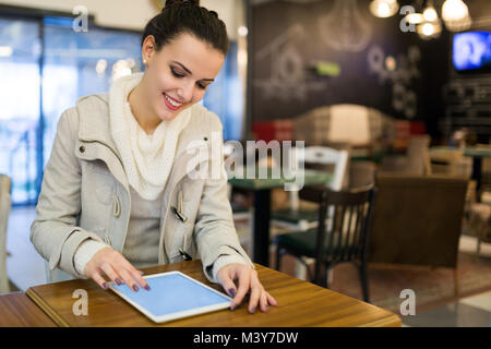 Attraktive junge Frau mit Tablette im Cafe Stockfoto