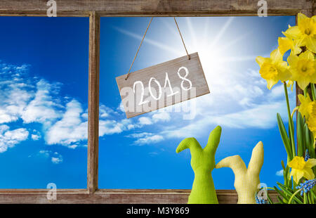 Mit Text 2018 Zeichen. Fenster mit Blick auf den schönen, sonnigen blauen Himmel. Osterhase und Narziss Vor Stockfoto